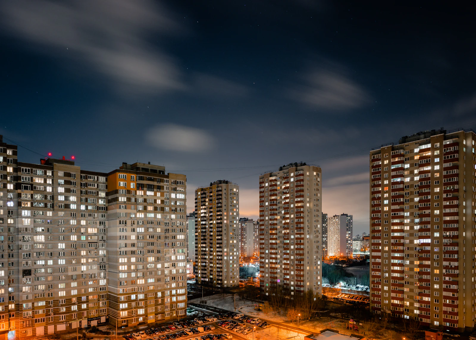 Fachada de un bloque de pisos con ventanas iluminadas de noche